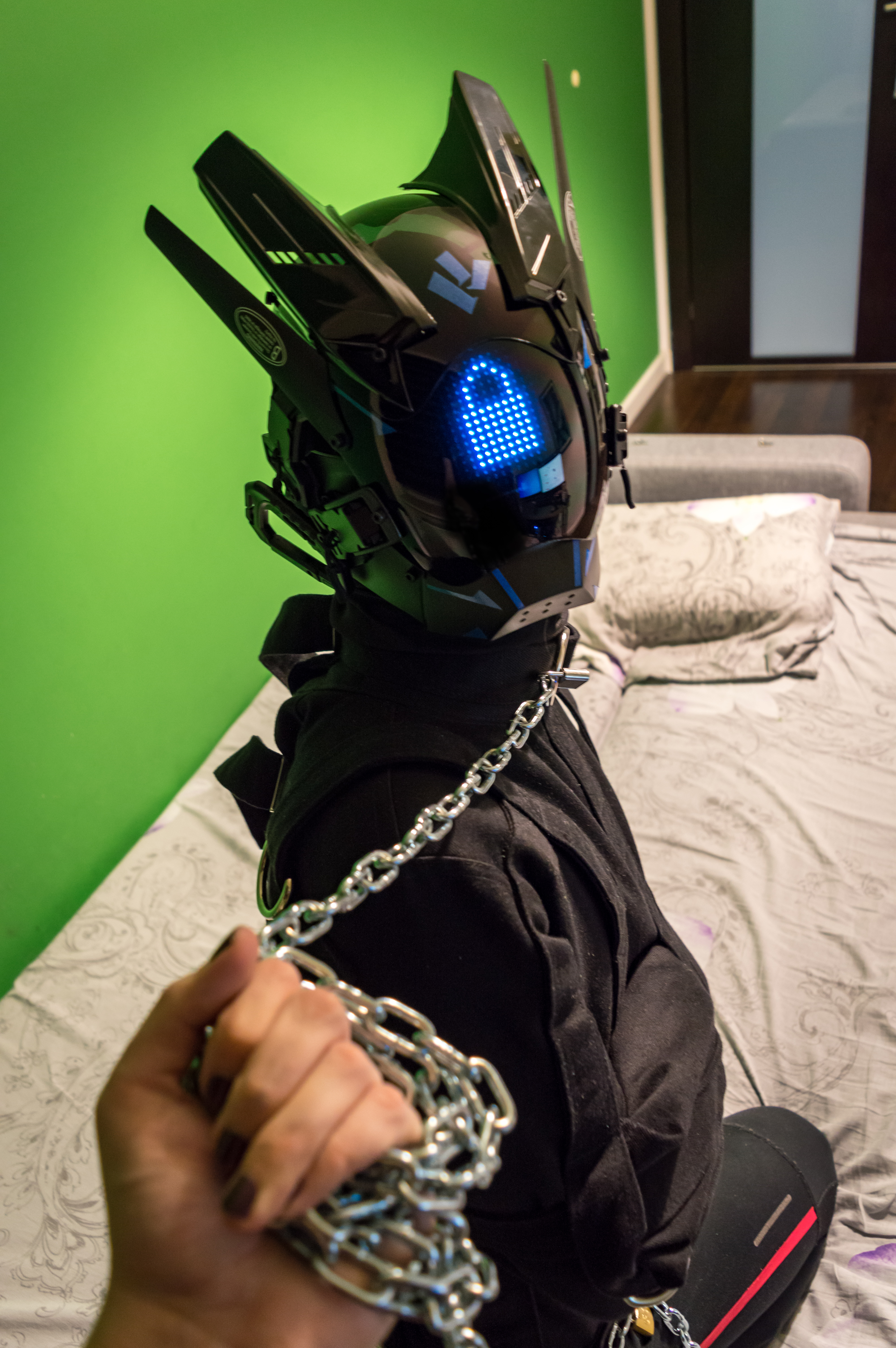 drone with full face visor, sitting on a bed on its knees wearing a straitjacket, being pulled towards the viewer by a hand holding a chain leash. there's a blue padlock symbol on the visor drone with full face visor, sitting on a bed on its knees wearing a straitjacket, being pulled towards the viewer by a hand holding a chain leash. there's a blue padlock symbol on the visor